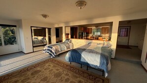 Ein geräumiges Schlafzimmer mit zwei Betten, einem großen Fenster und einer Glastür, die auf einen Balkon führt.