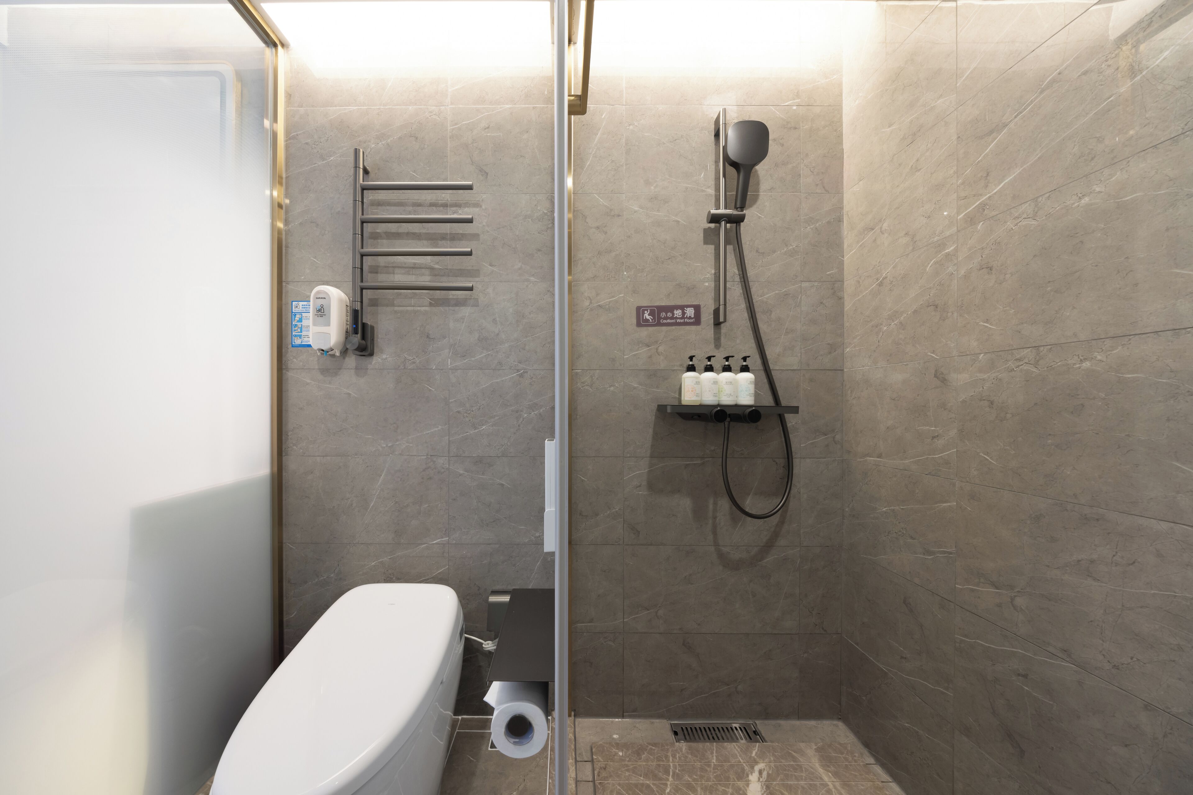Un baño moderno con ducha, inodoro y perchero para toallas.
