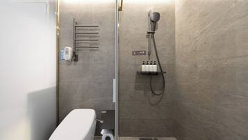 Un baño moderno con ducha, inodoro y perchero para toallas.