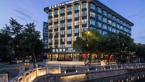 Un hotel moderno con un cartello ben visibile, diversi piani e un ingresso luminoso.