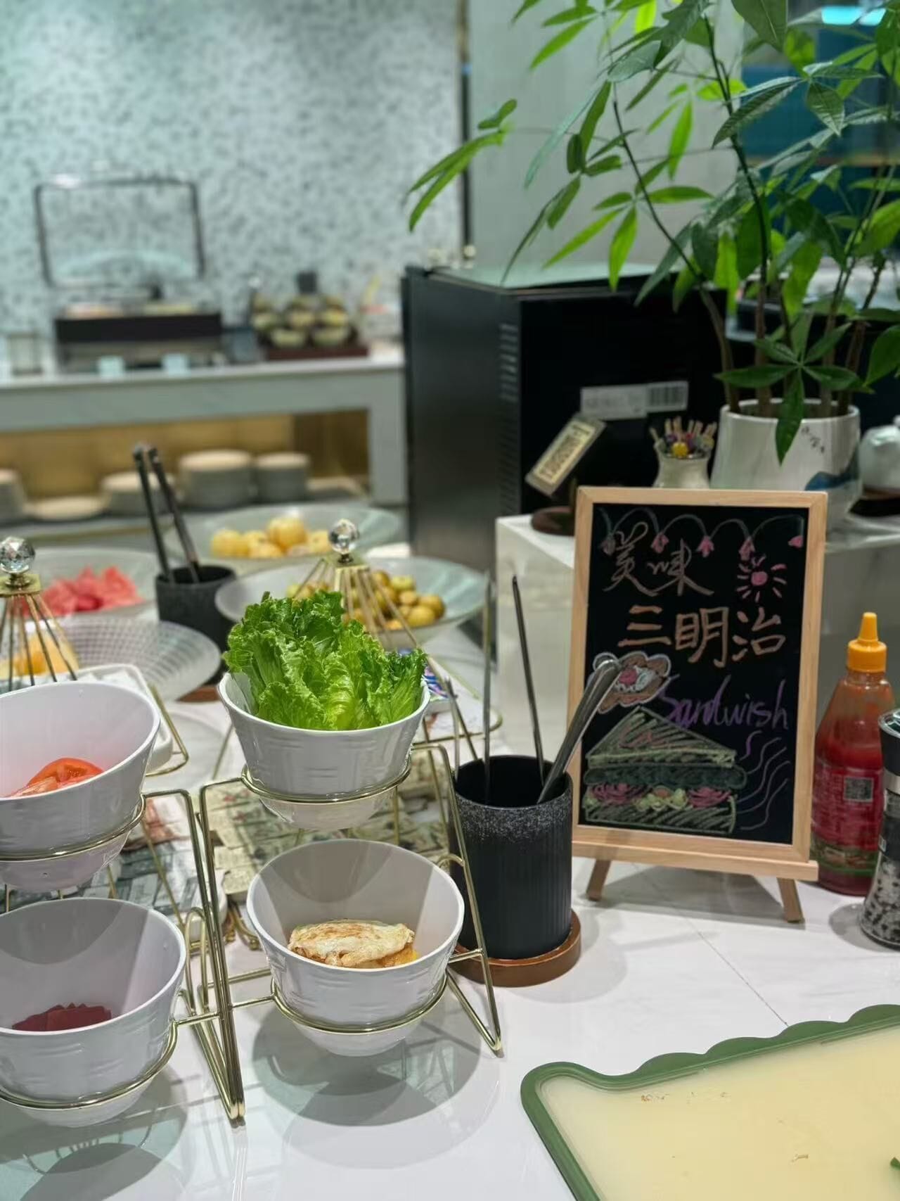Una mesa de buffet con distintos alimentos y un letrero en una pizarra.
