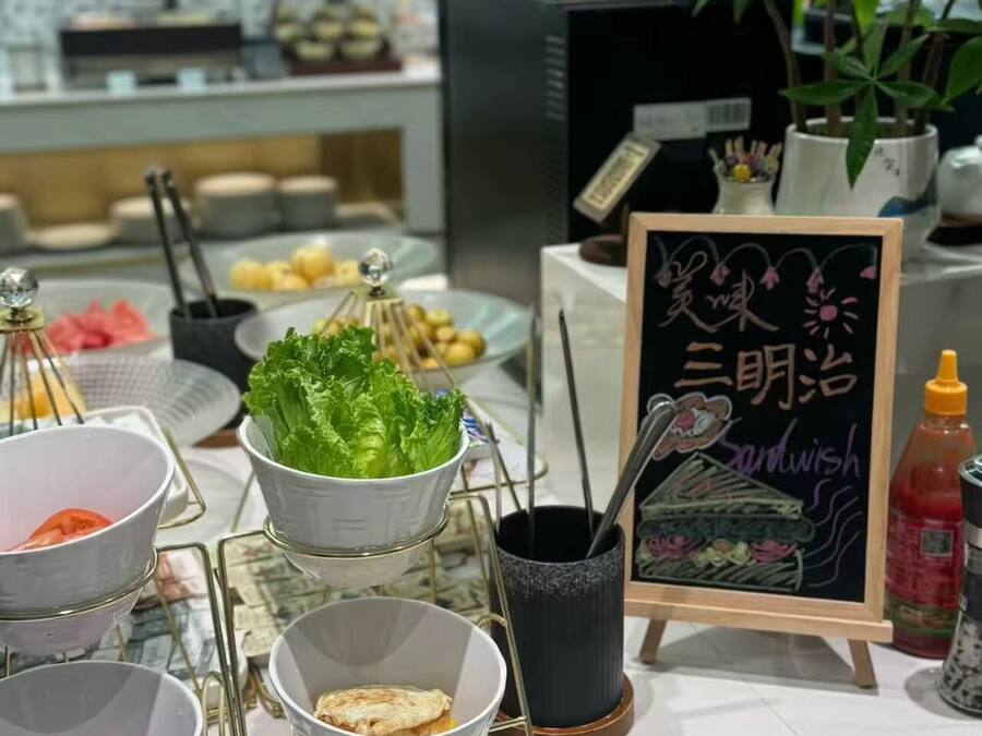 Una mesa de buffet con distintos alimentos y un letrero en una pizarra.