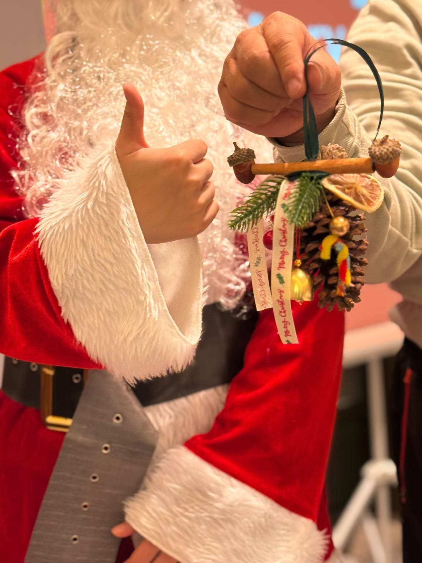A person in a Santa Claus costume holding a decorative ornament.