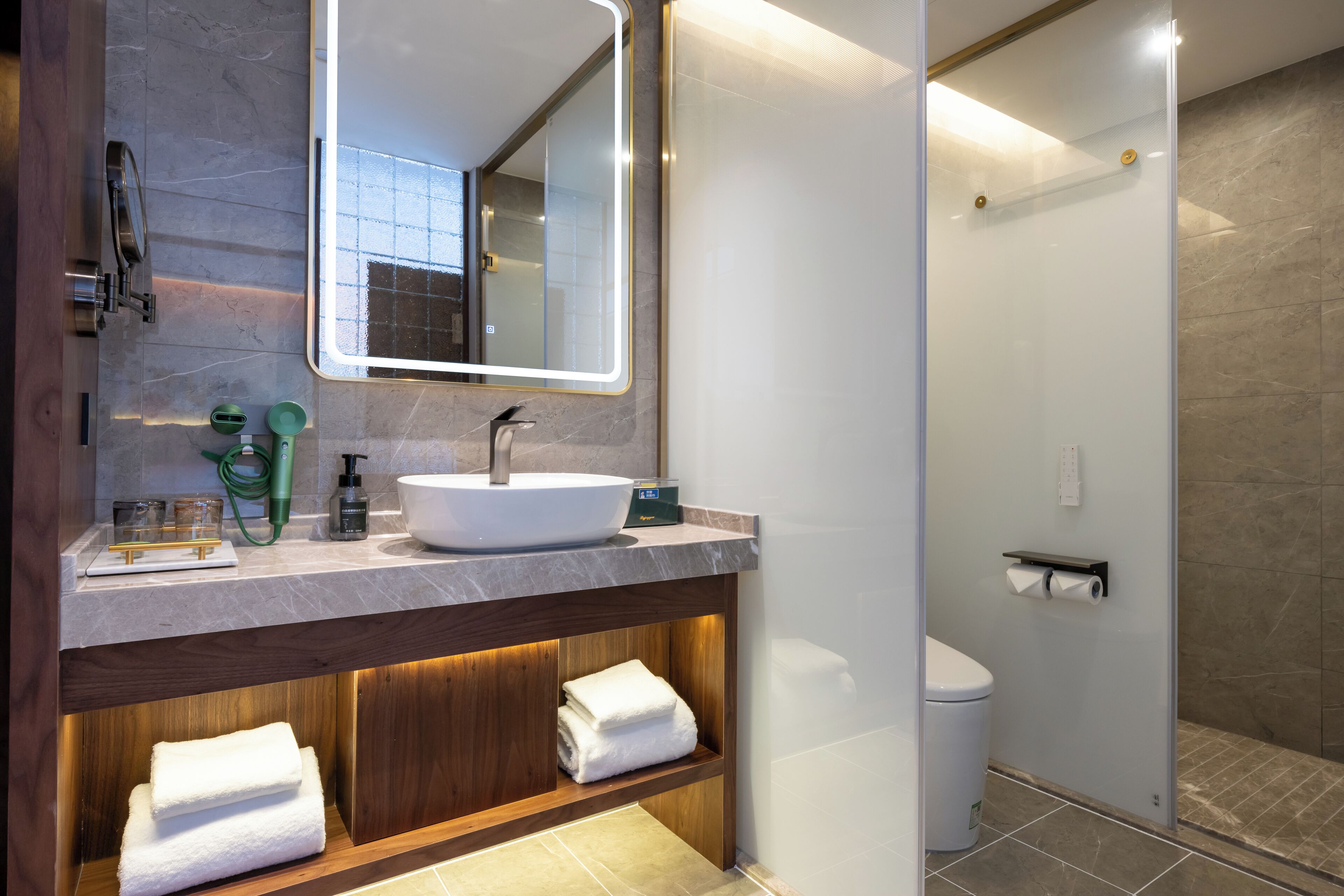 Ein modernes Badezimmer mit großem Spiegel, Waschbecken, Dusche und Toilette.