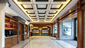 Una hall con reception, scaffalature in legno, pavimento in marmo e un grande murale.