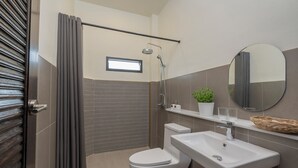 A modern bathroom with a shower, toilet, sink, and a small window.