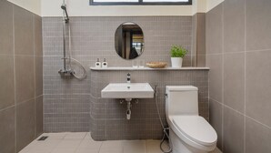 Een moderne badkamer met een douche, wastafel, toilet en een kleine potplant.