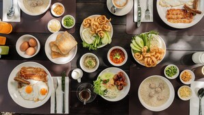 Een tafel met diverse ontbijtgerechten zoals eieren, spek, worstjes en rijst.