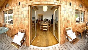 A wooden interior with a dining area, wooden walls, and a glass door leading to another room.