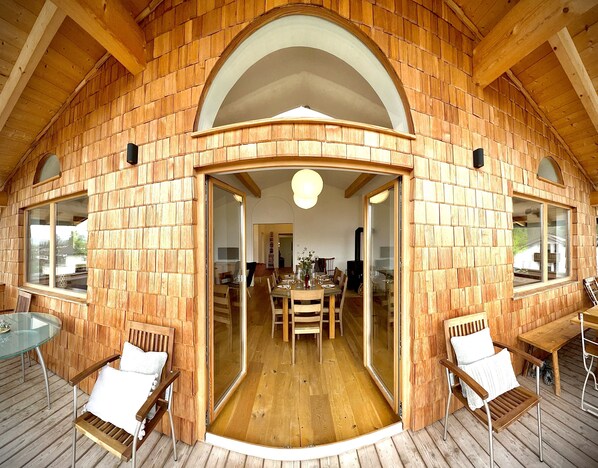 A wooden interior with a dining area, wooden walls, and a glass door leading to another room.