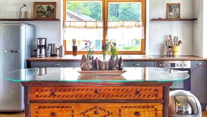 A kitchen with a glass-top island, wooden cabinetry, a refrigerator, and a stove.