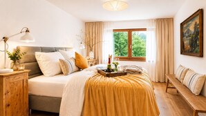 A bedroom with a bed, bedside table, lamp, and a window with curtains.