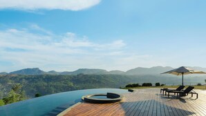 A infinity pool with a wooden deck, lounge chairs, and an umbrella. - Uga Halloowella - Hatton - All Inclusive (Norwood)