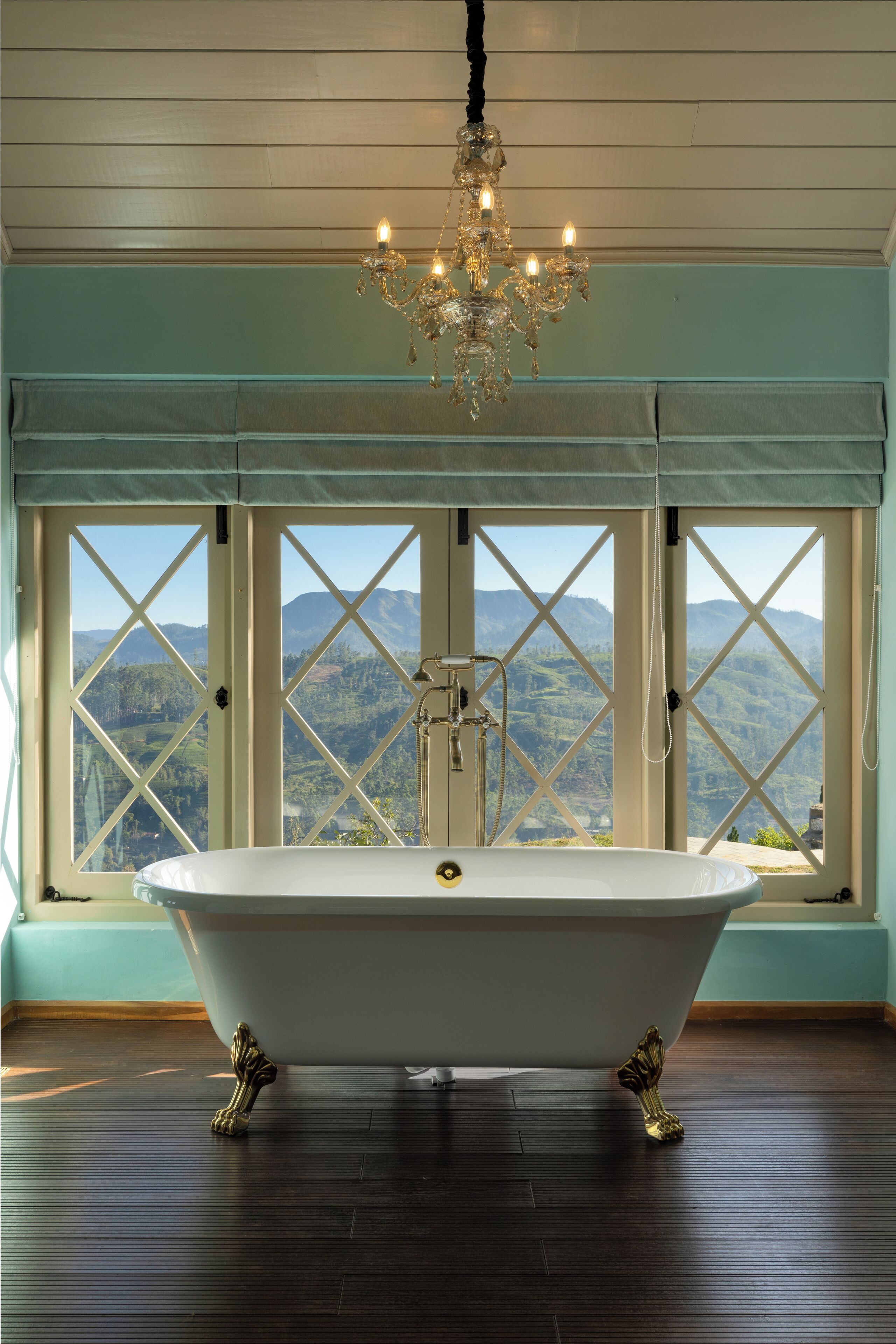 A freestanding bathtub in a room with large windows overlooking a mountainous landscape.