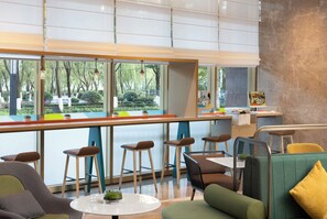 A modern interior with a bar area, seating, and large windows offering a view of greenery.