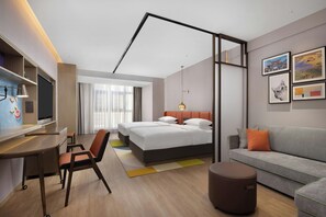 A modern hotel room with a bed, a desk, a chair, a sofa, and a TV. - Home2 Suites BY Hilton Kunming Xishan (KUNMING)