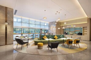 A modern interior with seating arrangements, a coffee bar, and large windows. - Home2 Suites BY Hilton Kunming Xishan (KUNMING)