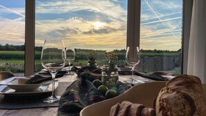 A table set for two with wine glasses, a vase with flowers, and a plate of food.