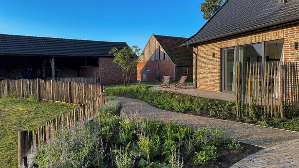 A residential area with brick houses, a wooden fence, and a garden with flowers and plants.