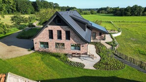 A modern house with a sloped roof, brick exterior, and a paved driveway.