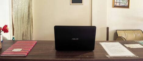A laptop on a desk with a framed sign reading "OYO" and a framed picture on the wall.