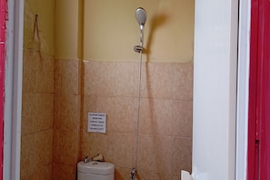 A bathroom with a shower, a toilet, and a sign on the wall.
