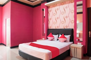 A modern hotel room with a large bed, red walls, and a patterned wallpaper.
