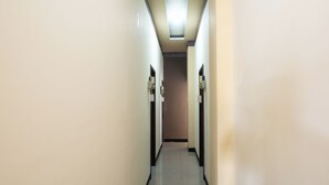 Un couloir étroit et bien éclairé, doté d’un sol carrelé, qui mène à une porte au fond.