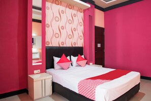 A modern bedroom with a large bed, pink walls, and a patterned headboard. - Hotel O Homestay Puspa Gemilang Syariah (Palembang)