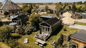A modern outdoor living area with a glass enclosure, picnic tables, and a wooden deck.