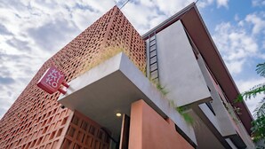 A modern building with a unique lattice facade, a visible sign indicating a parking area, and a clear sky in the background. - Kumiko Apartment (Canggu)