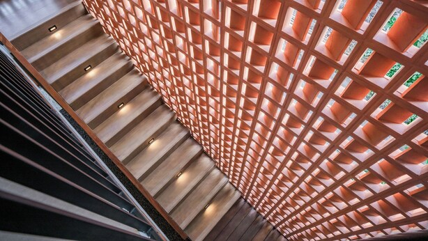 A staircase with wooden steps and a lattice wall with illuminated panels. - Kumiko Apartment (Canggu)