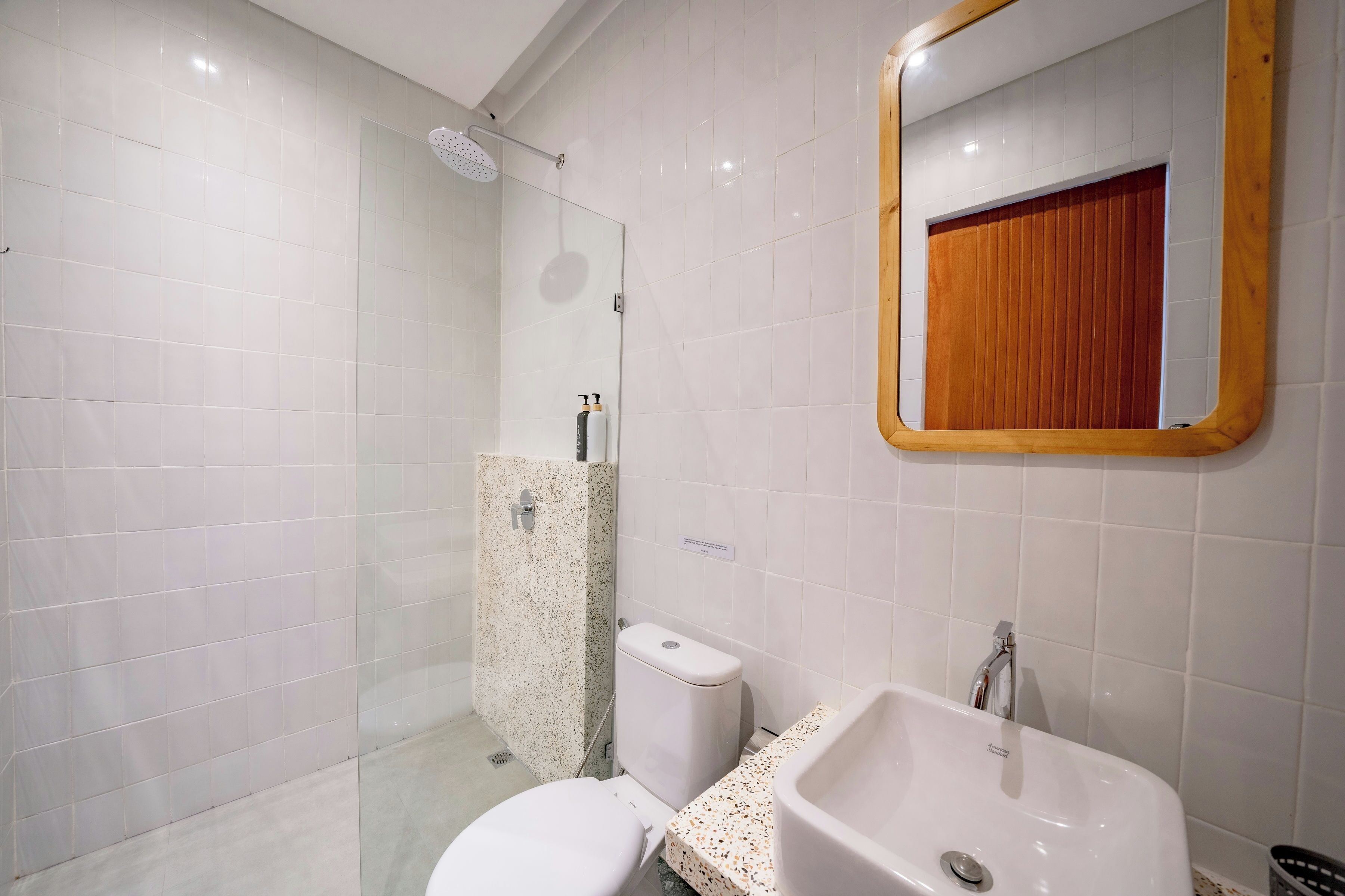 A modern bathroom with a glass shower enclosure, a toilet, and a sink with a mirror above.