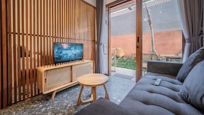 A modern living room with a television, wooden panel wall, and a sofa with a remote control. - Kumiko Apartment (Canggu)