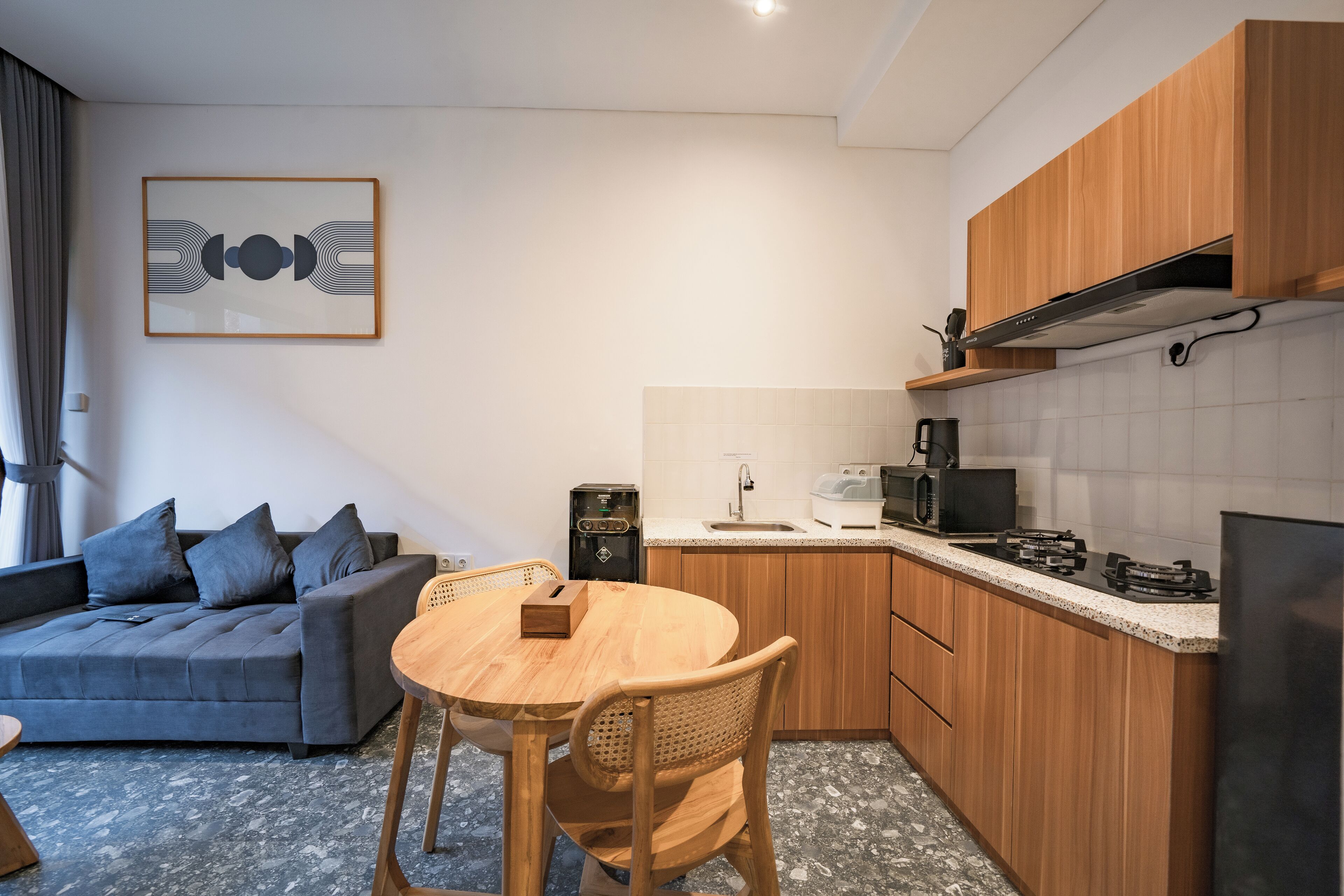 Un espace de vie compact comprenant un canapé, une table à manger et un coin cuisine.
