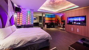 Ein modernes Hotelzimmer mit einem großen Bett, einem an der Wand befestigten Fernseher und einem außergewöhnlichen Deckenstil.