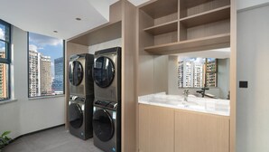 Un baño moderno con lavadora y secadora integradas, un espejo grande y vistas a rascacielos.