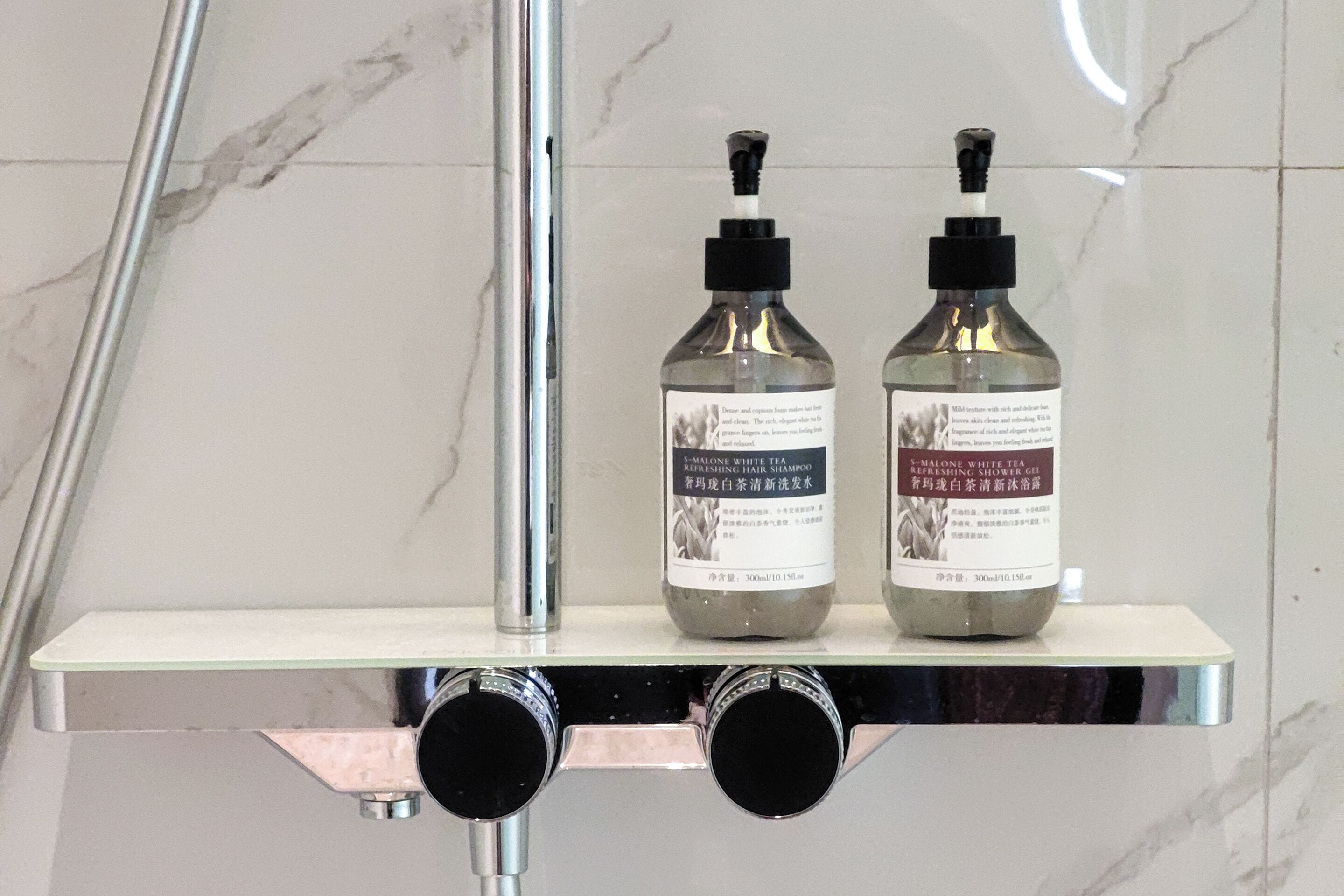 Two bottles of shampoo on a bathroom shelf.