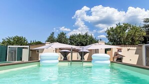 A swimming pool with clear water, surrounded by umbrellas and a building with a beige facade. - Da Lisa by Interhome (Cecina)