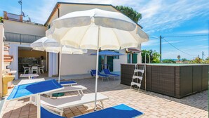 A poolside area with lounge chairs and umbrellas, a hot tub, and a barbecue grill. - Da Lisa by Interhome (Cecina)