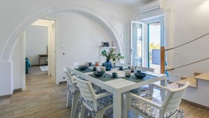A dining area with a white table and chairs, a potted plant, and a view of the outside. - Da Lisa by Interhome (Cecina)