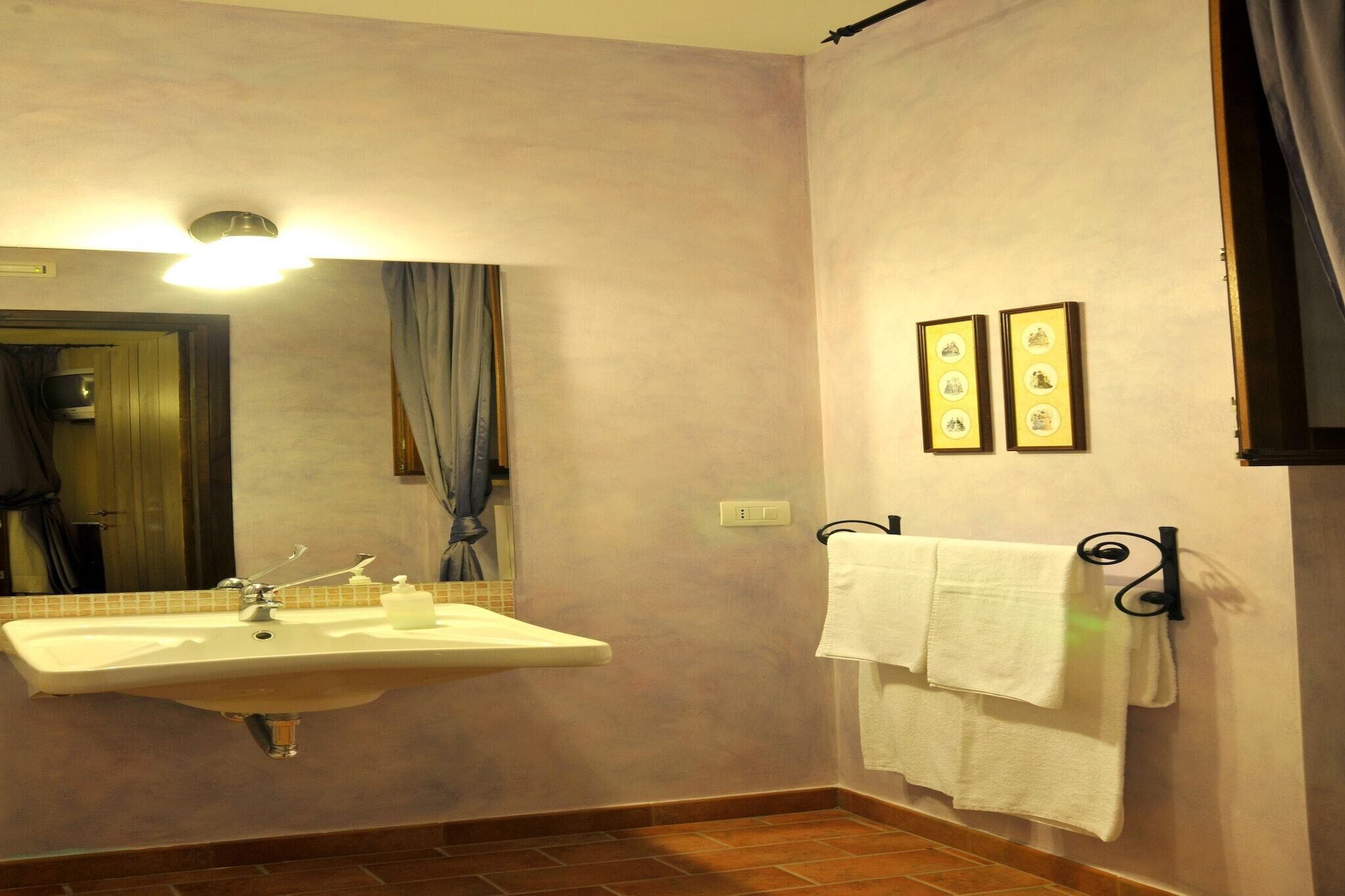 A bathroom with a sink, mirror, towel rack, and framed pictures on the wall.
