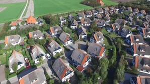 An aerial view of a residential area with houses having sloped roofs and a mix of red and grey colors. - Villa in Callantsoog with Whirlpool and Beach (Callantsoog)
