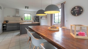 A modern kitchen with a wooden island, pendant lights, and a clock on the wall.