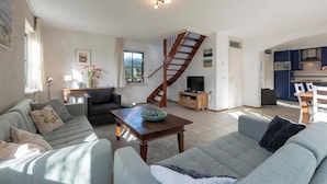 A spacious living area with a sofa set, a wooden coffee table, and a staircase leading to an upper level. - Villa in Callantsoog near the Beach (Callantsoog)