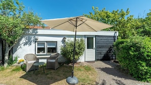 A modern house with a patio area featuring wicker furniture, a table, and a large umbrella. - Holiday Home in Callantsoog near Beach (Callantsoog)