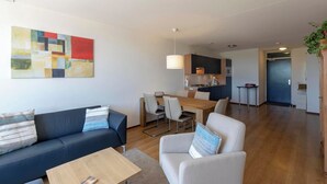 Eine moderne Wohnung mit Essbereich, Küchenzeile und Wohnzimmer mit Sofa und Sessel.