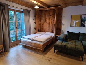 A room with a wooden bed, a sofa, and a window with curtains.