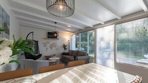 Una sala de estar moderna con comedor, que cuenta con un amplio ventanal, una lámpara colgante y un mapa mundial en la pared.