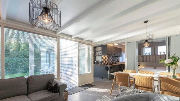 Una sala de estar moderna con un sofá, un comedor con mesa y sillas, y una cocina al fondo.